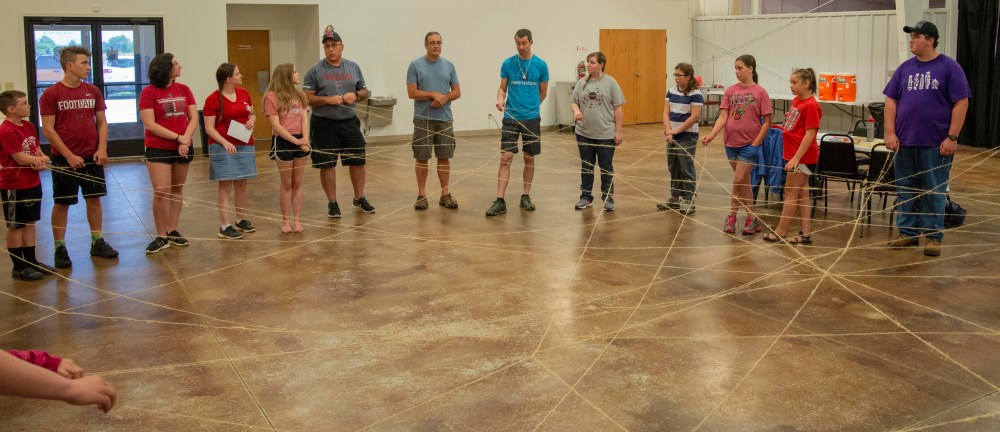 A group of people connected by twine strings to form a web.