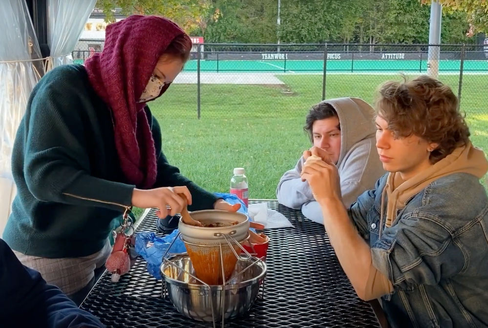 A student uses a pestle and food mill to process persimmon berries.