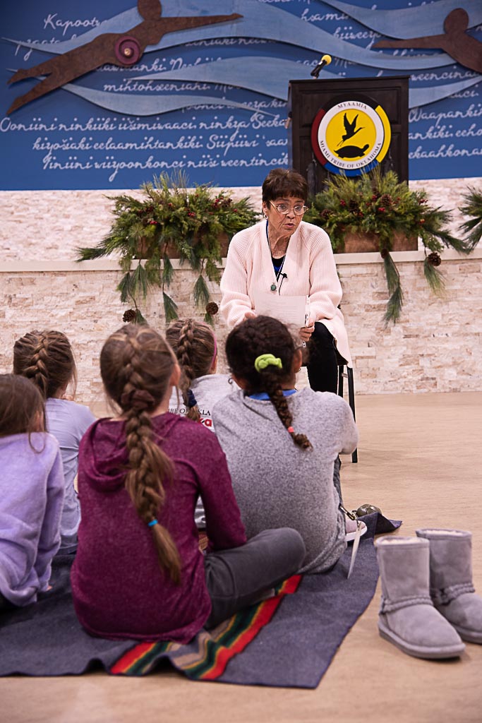 A tribal elder reading a story to children in the audience