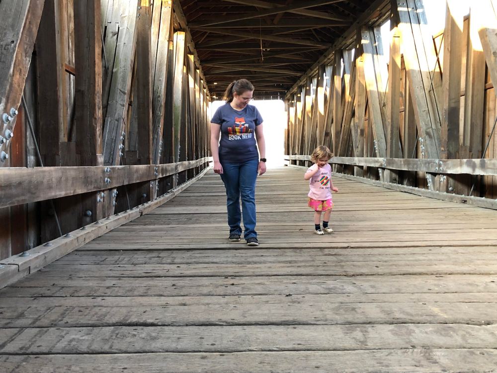 Mother and young child walking toward the camera on a covered bridge