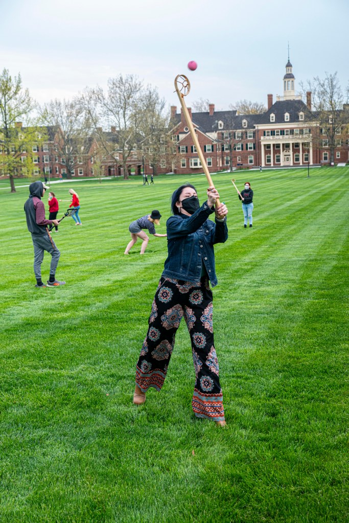 Myaamia student throwing a ball with a wooden lacrosse stick