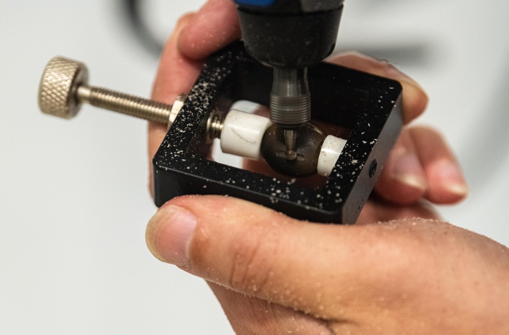 A Kentucky coffee bean being engraved by a dremel