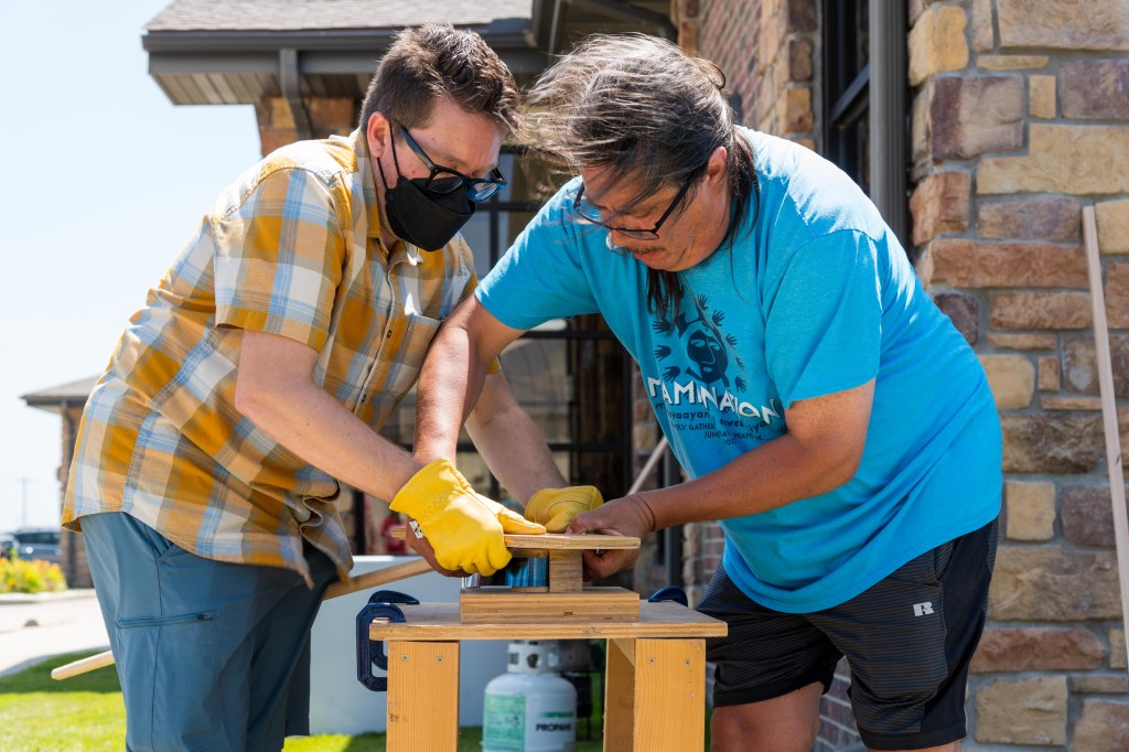 Two men standing over a jig