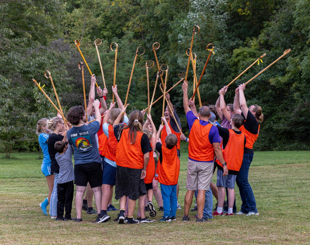 Players in a huddle raising their lacrosse sticks in the air