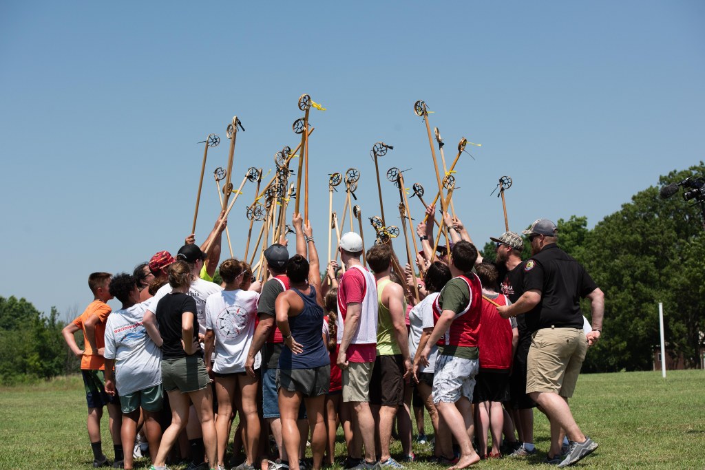 People in a huddle raising their lacrosse sticks