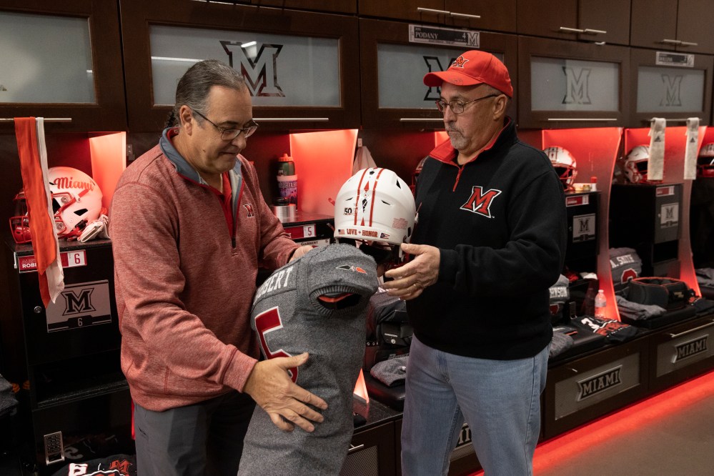 Two men looking that the Miami University football jerseys featuring the Myaamia Heritage Logo