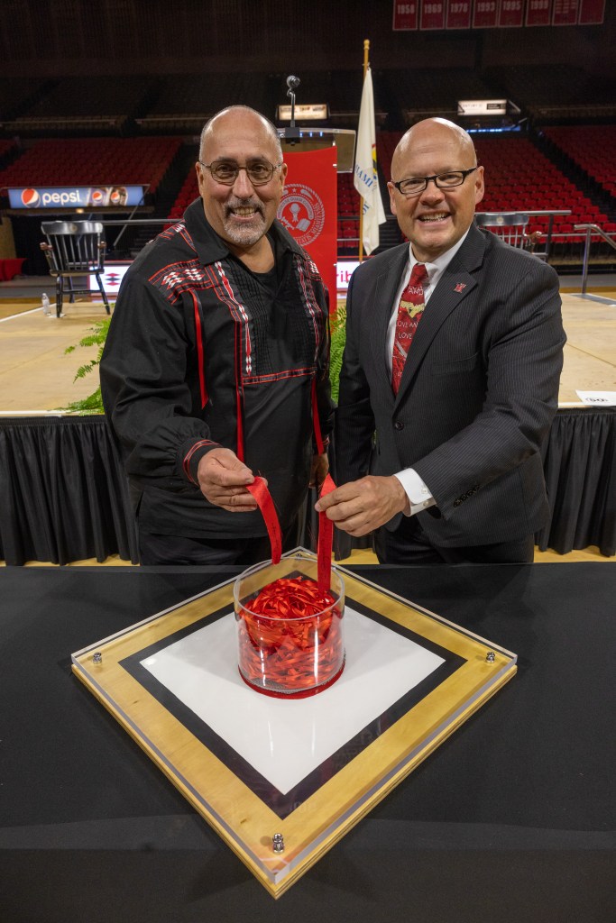 Chief Lankford and President Crawford placing red ribbons in a representation of the center diamond of the Myaamia Heritage Logo