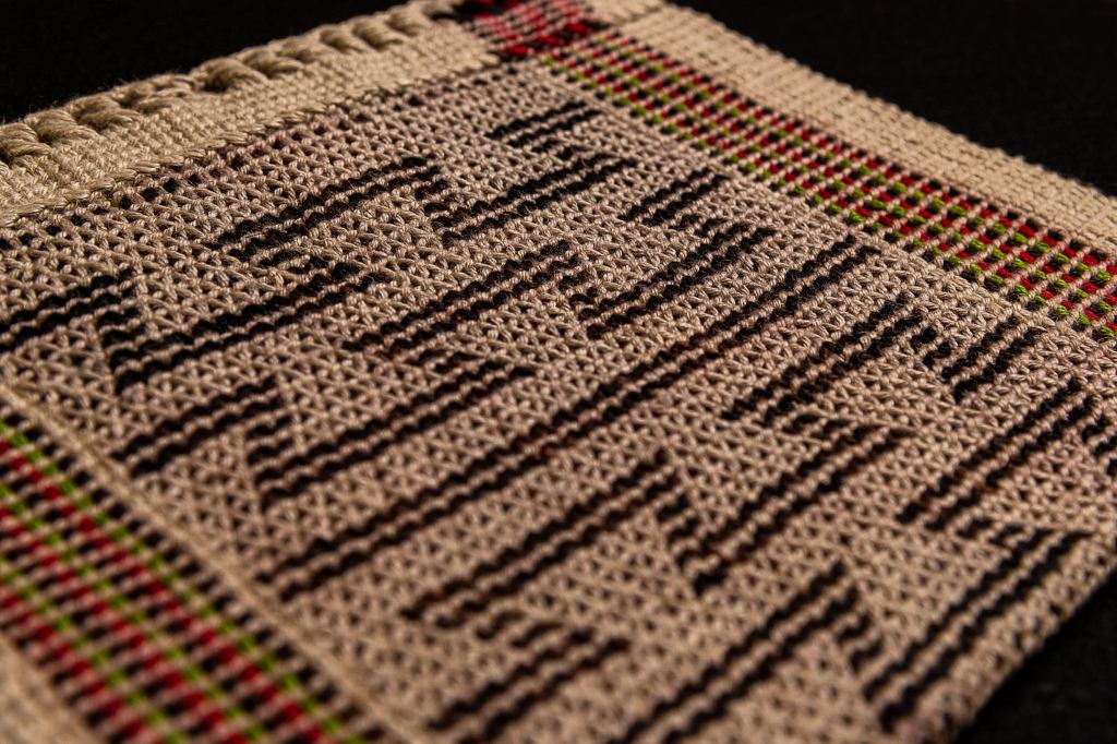 A close up of a twine bag with a pattern of jagged horizontal lines