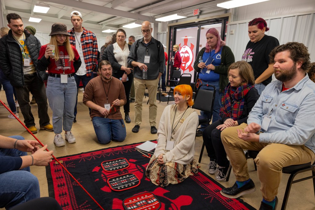 People gathered around a set of moccasin game pads