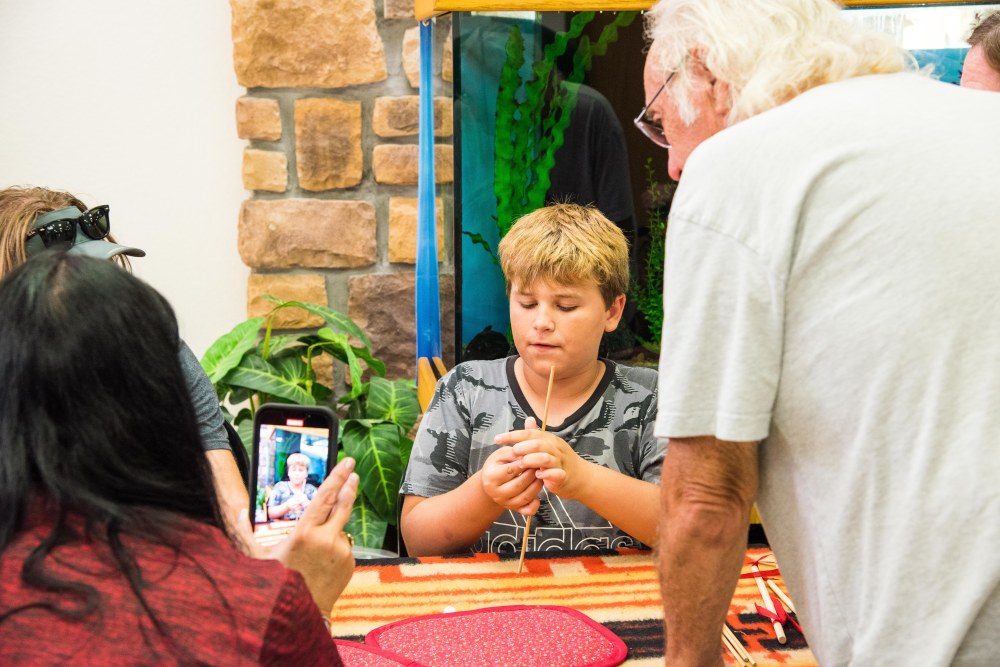 Boy showing a counting stick with adults watching