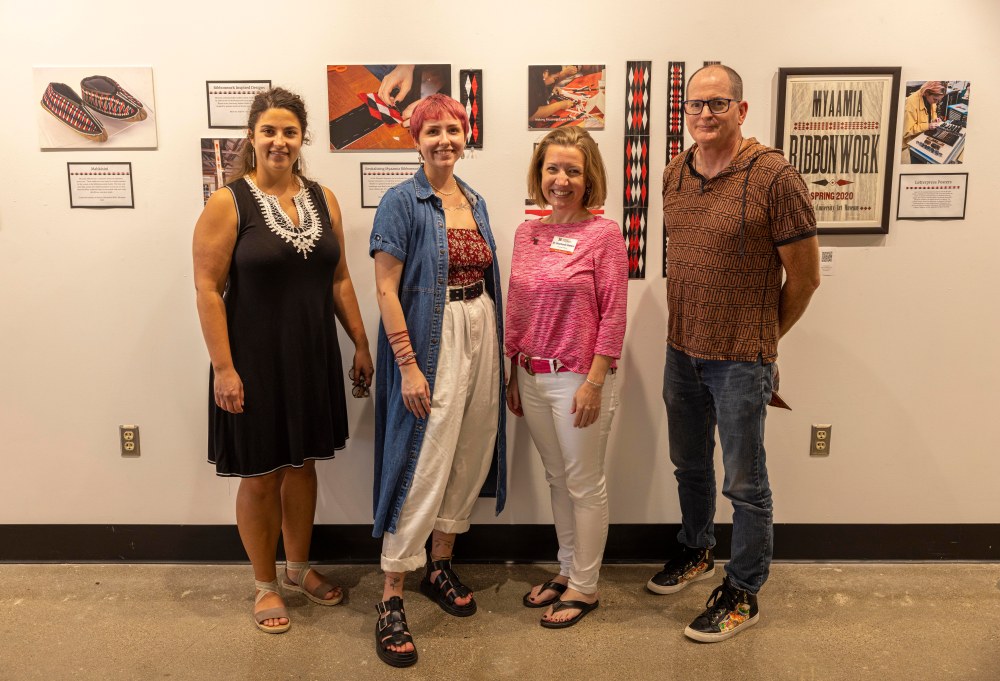 Four people standing in front of an exhibit wall