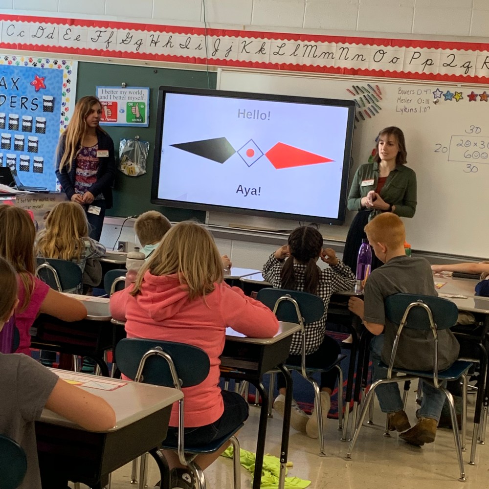 Two university students teaching a group of fourth graders