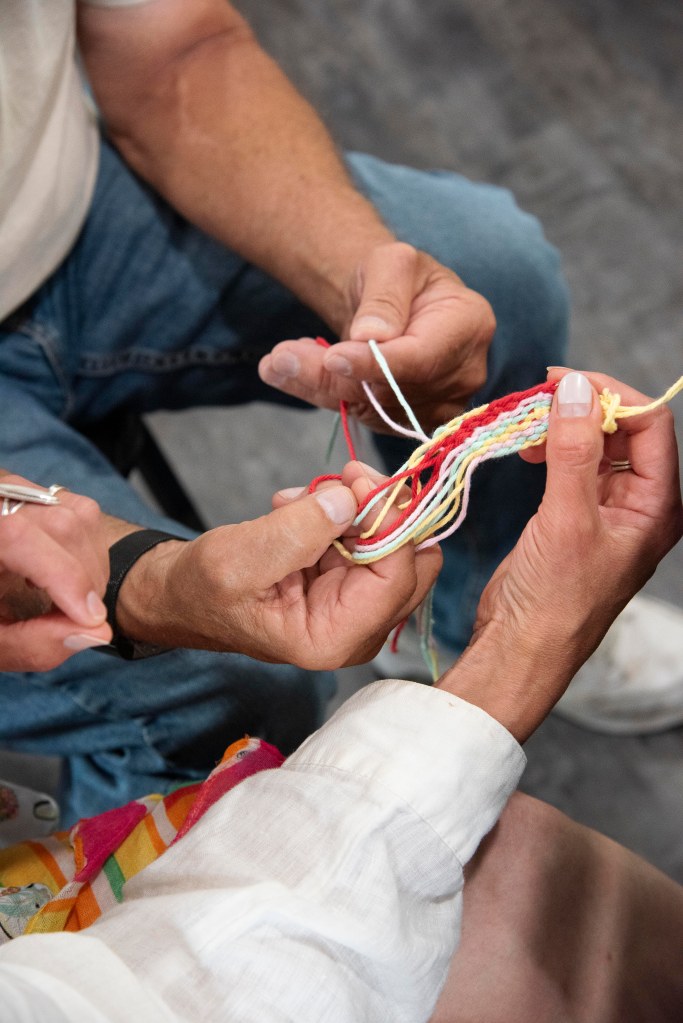 Two sets of hands working with a yarn keychain