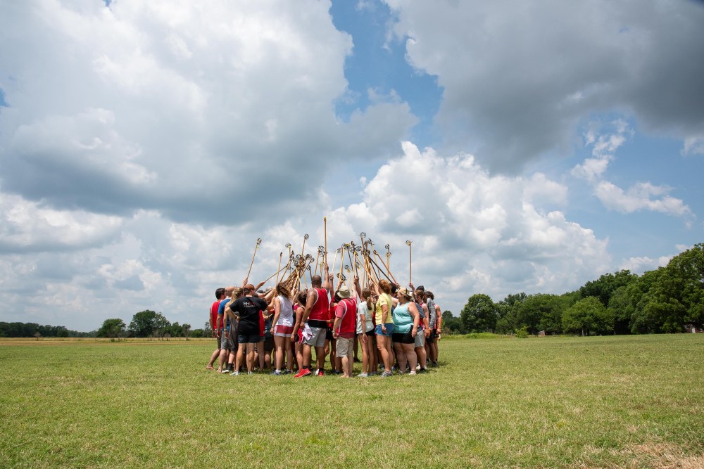 A group of people huddled together with their lacrosse sticks in the air