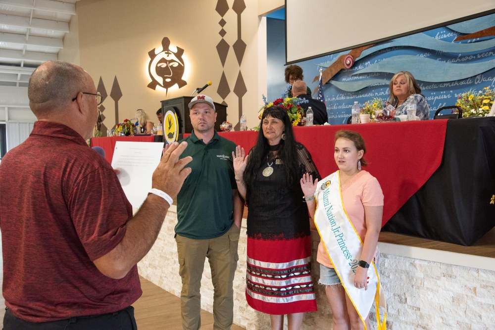 A man and two women with their right hands raised as they are being sworn into office