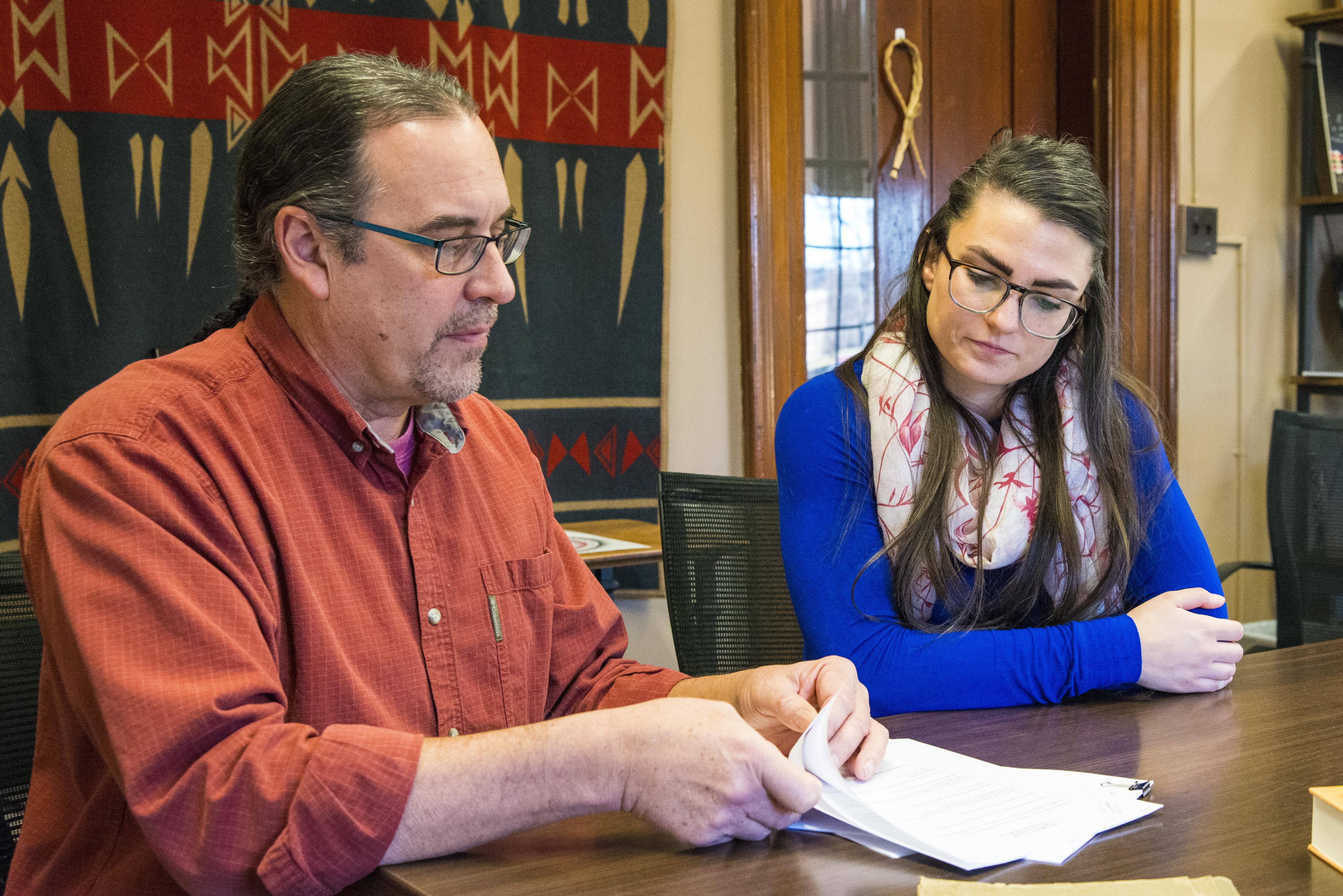 A man and a woman sit at table reading through documents together