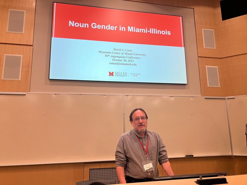 A man posing for the camera under a projector screen