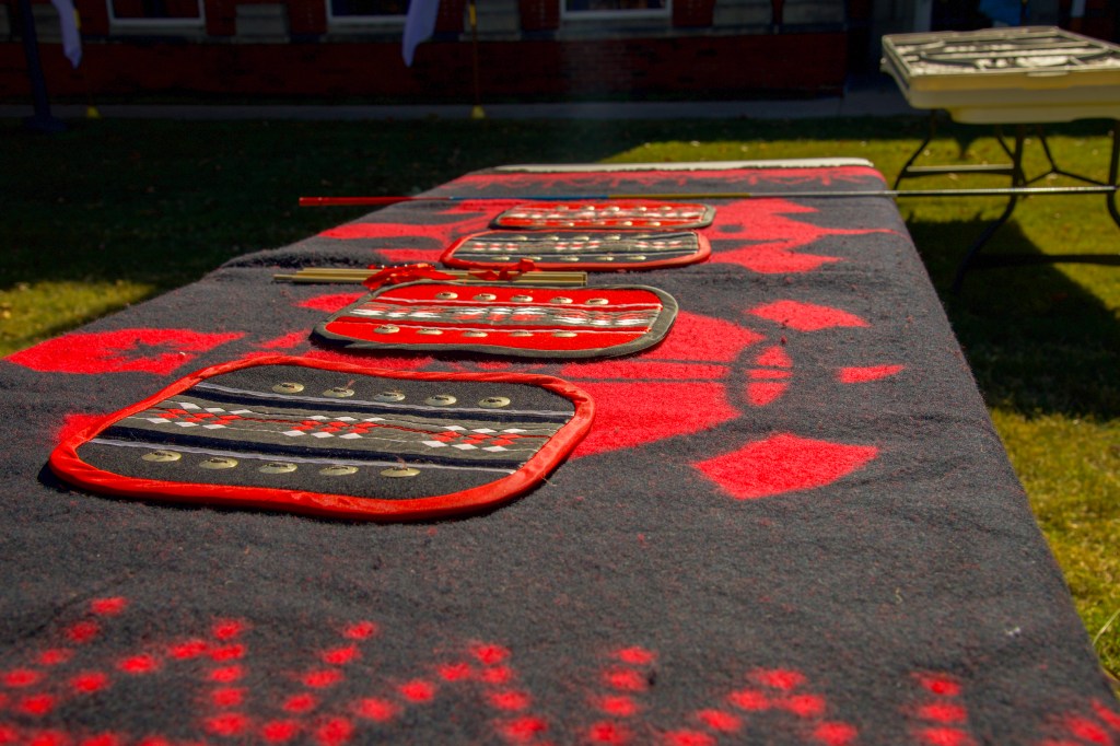 A table covered with a blanket and four moccasin game pads set out on top