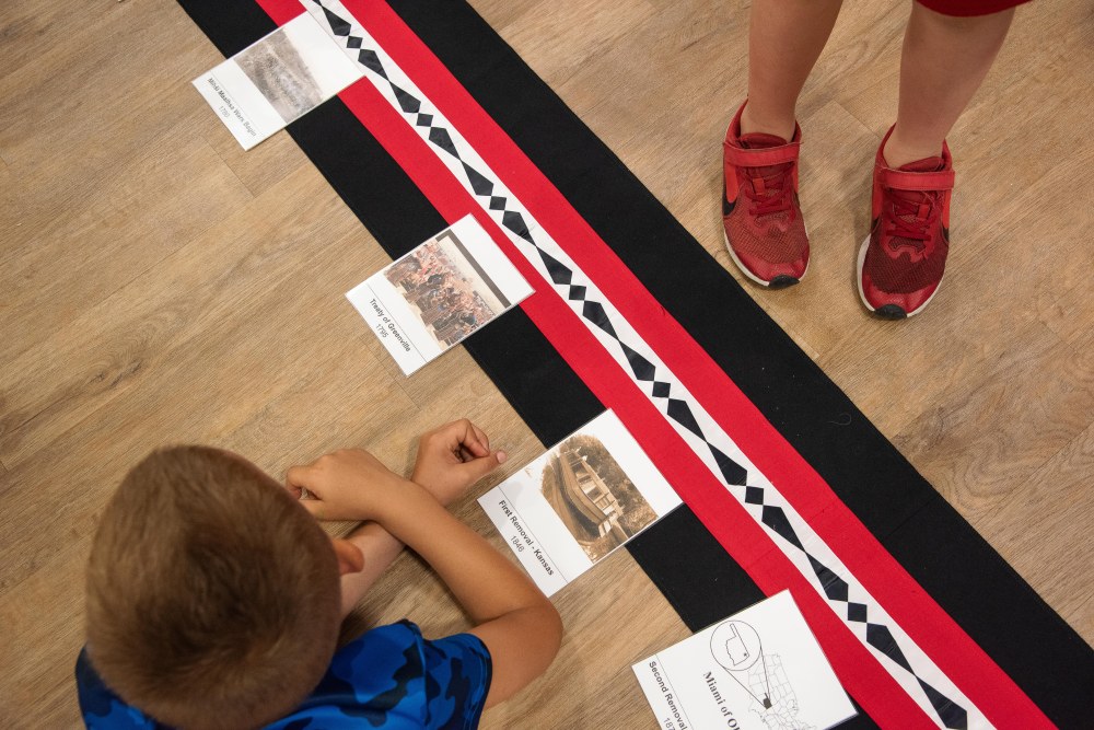 A young boy arranges cards into sequential order to create a timeline