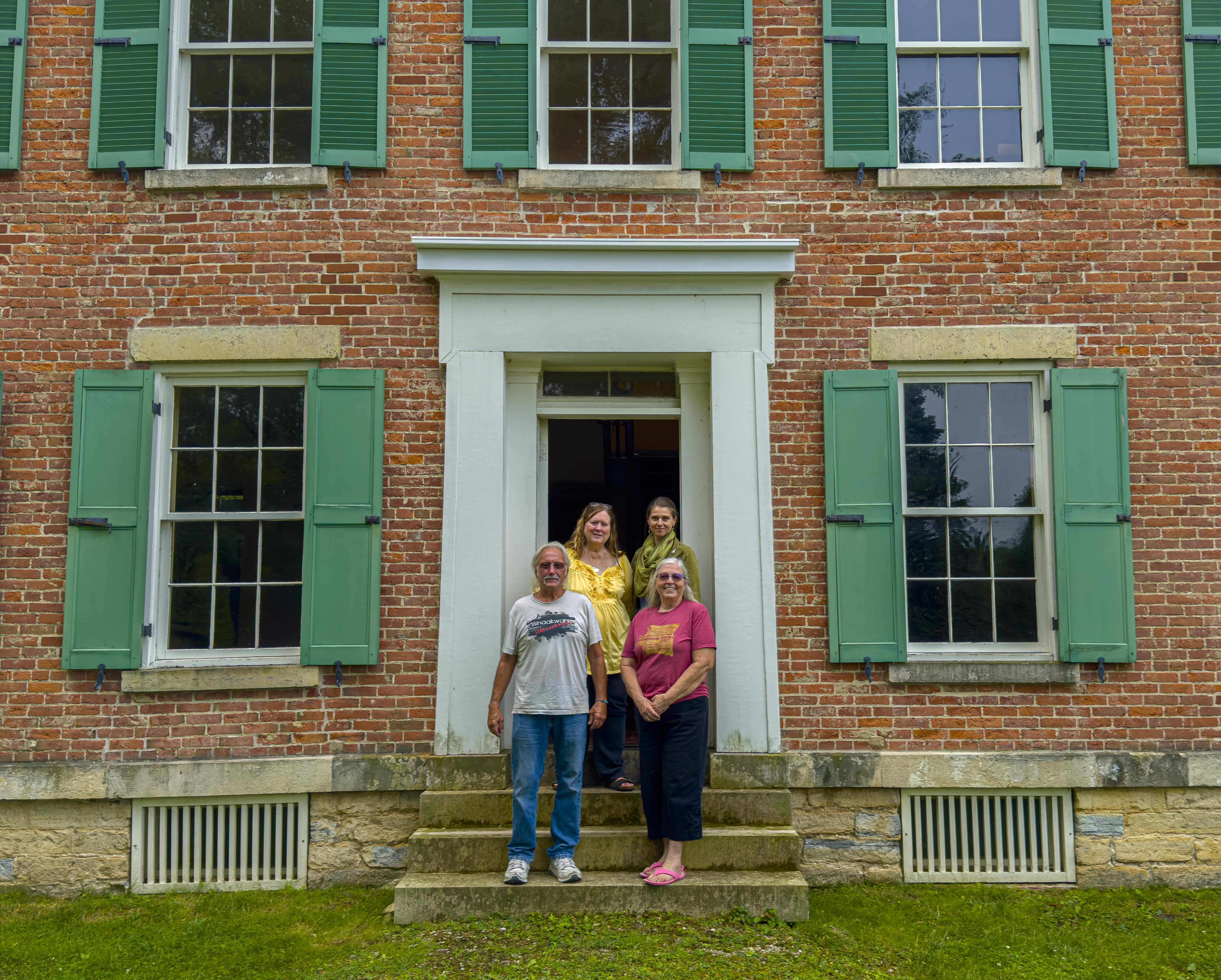 A group of four people pose for a photo in front of a large brick building