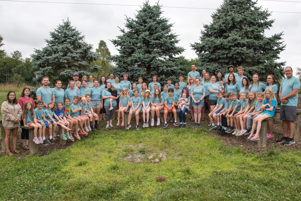 A group of about 50 adults and children pose for a photo outside