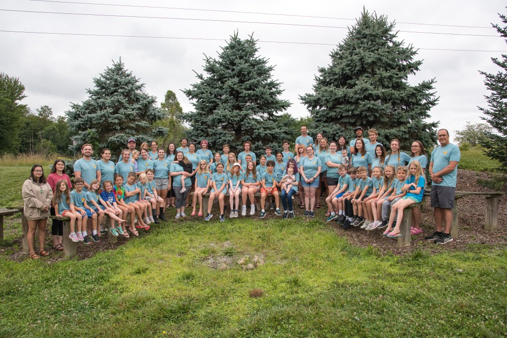 A group of about 50 adults and children pose for a photo outside