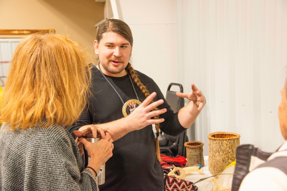 A man is talking to a woman about his artwork