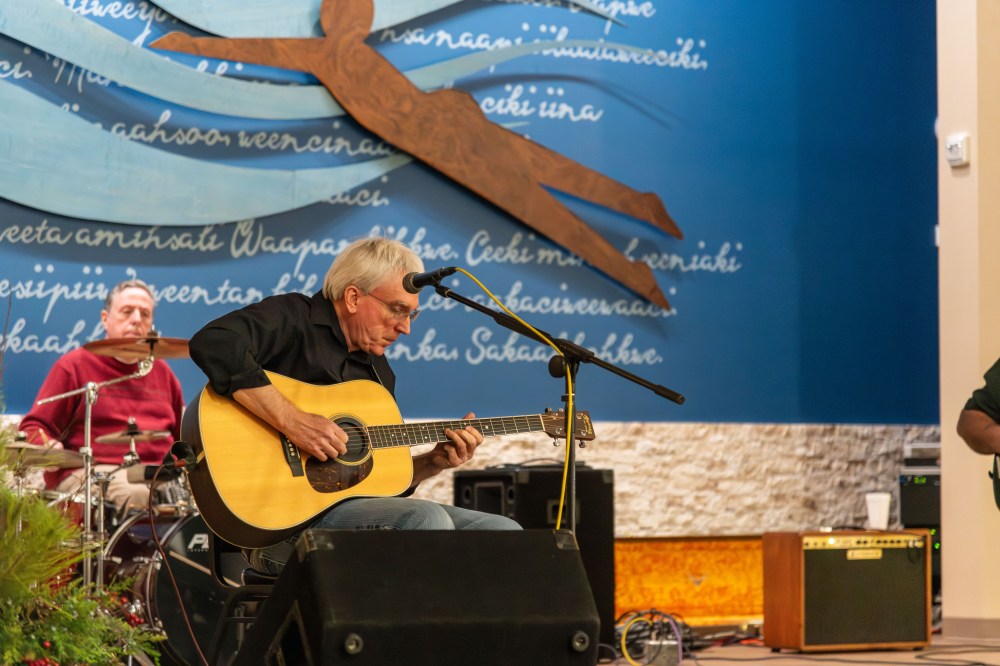 A man sits on stage playing a guitar