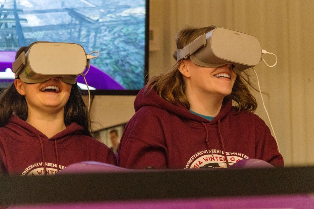 A child and adult sit side-by-side wearing VR headsets over their eyes