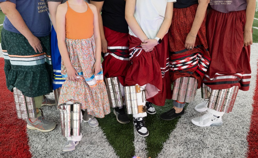 7 women stand together, holding up their stomp skirts to show off their shaker cans