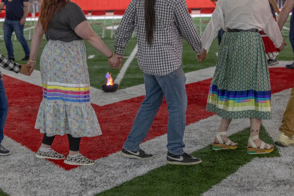 3 people hold hands around a fake fire
