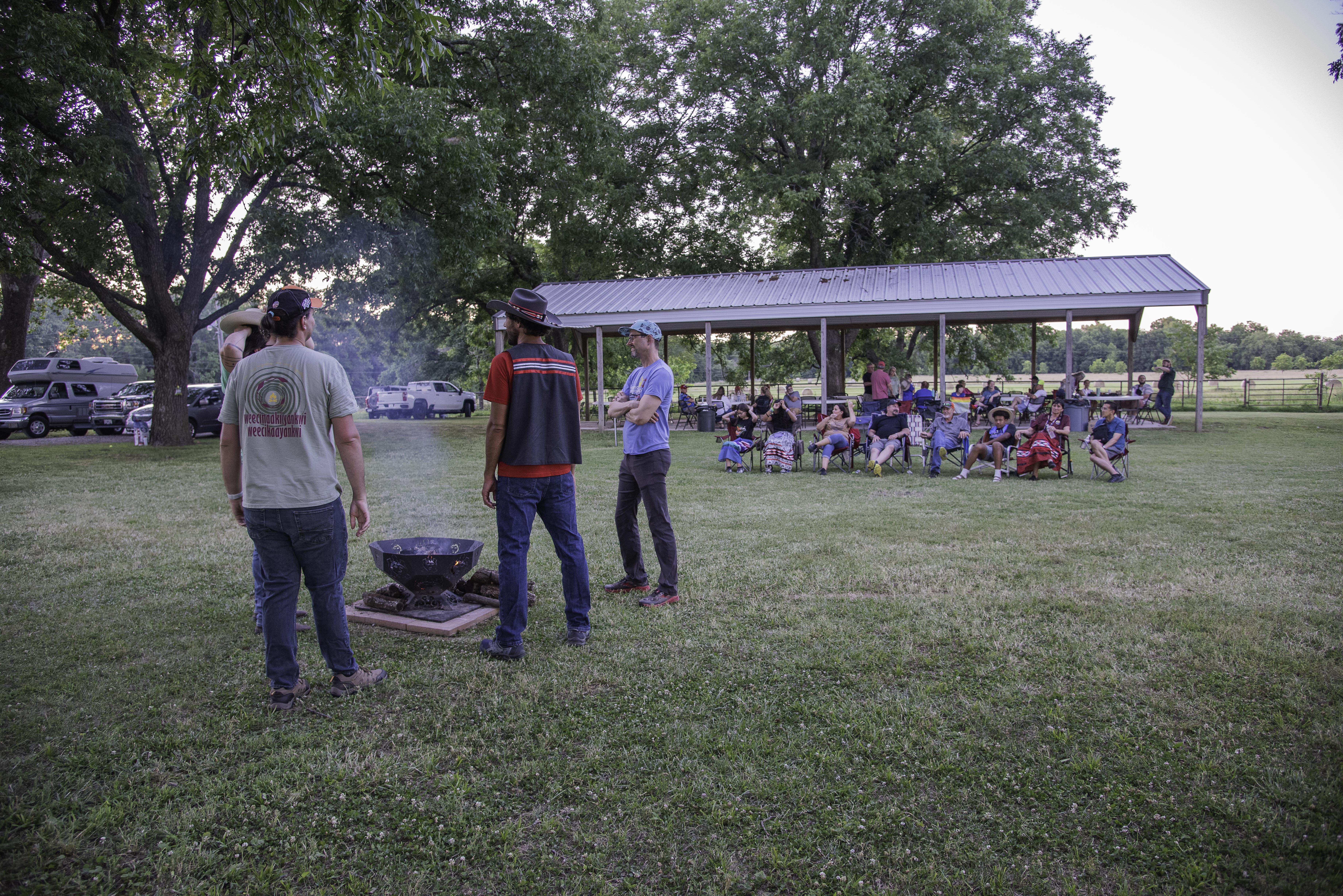 Four men stand around a small fire