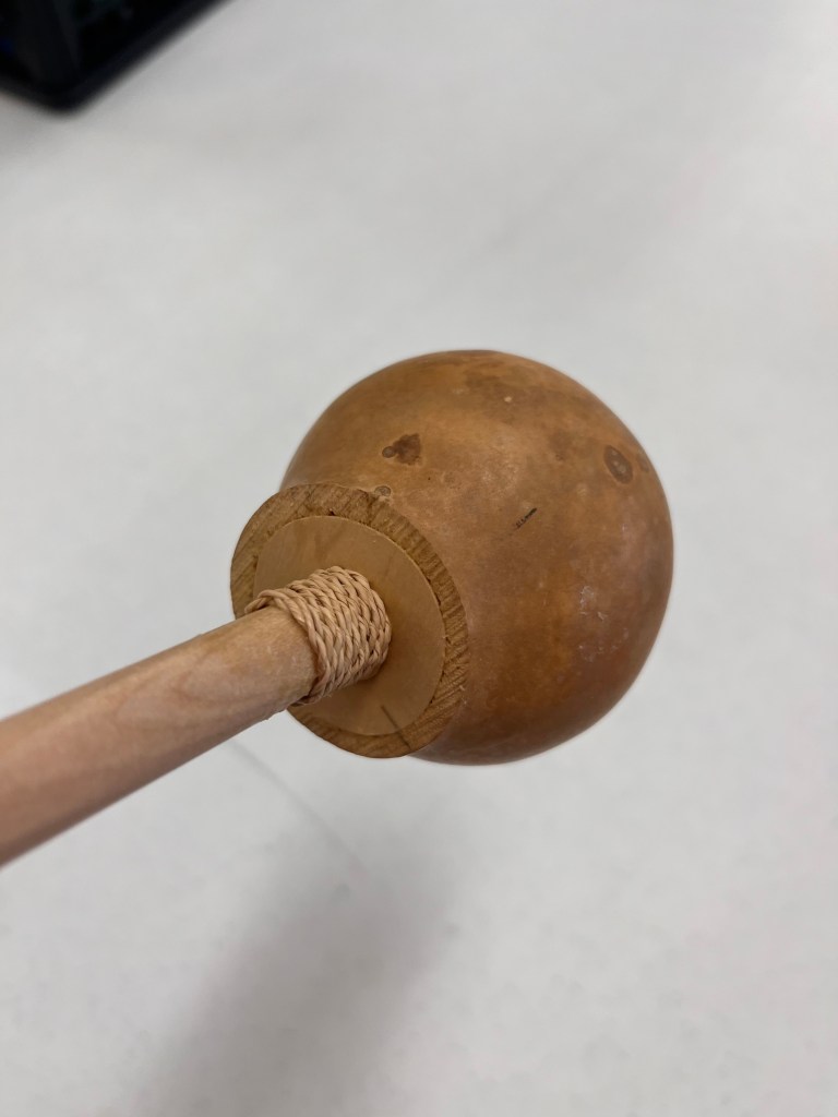 A small piece of cordage is wrapped around the base of the gourd