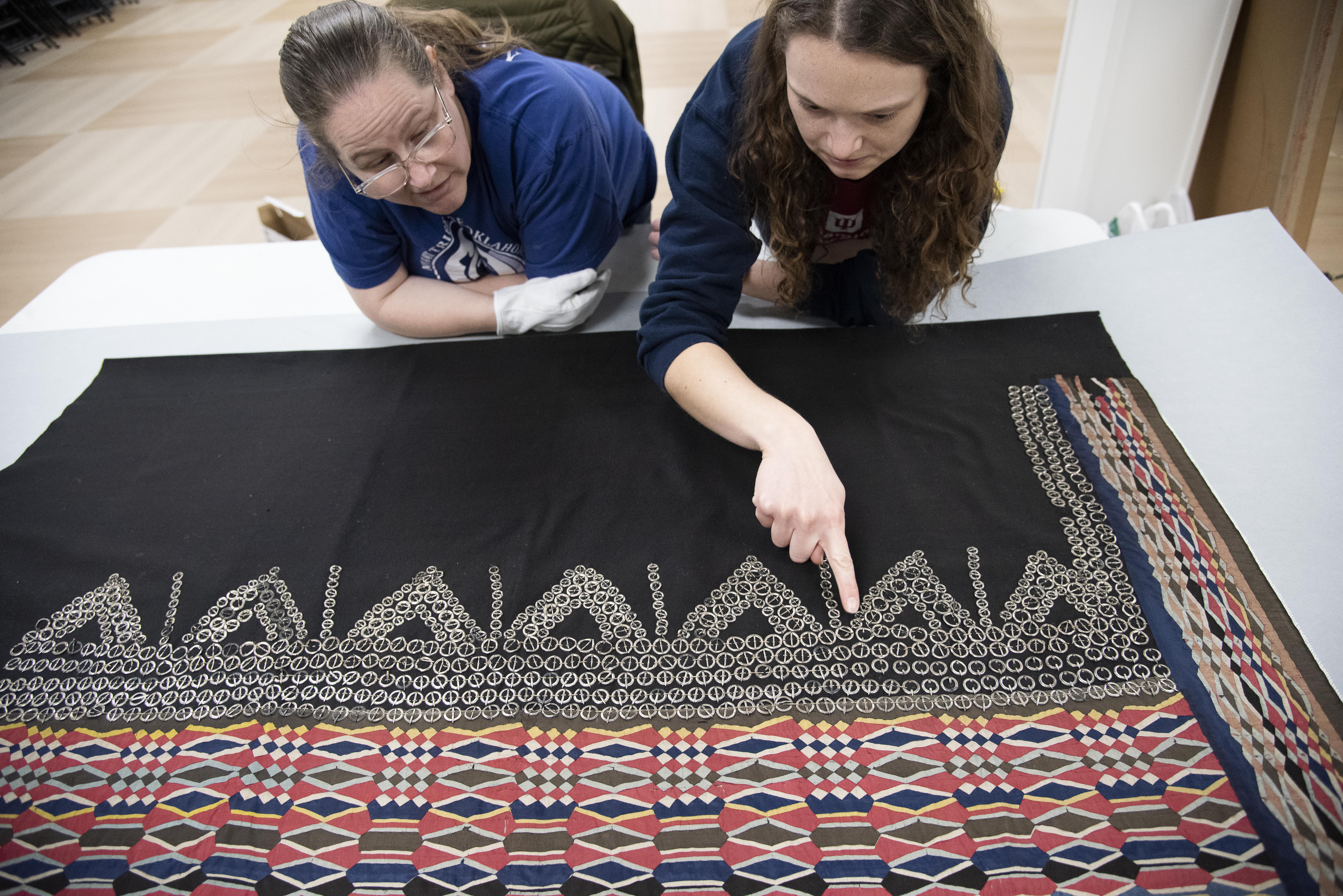 MHMA staff stand over a wrap skirt with ribbonwork