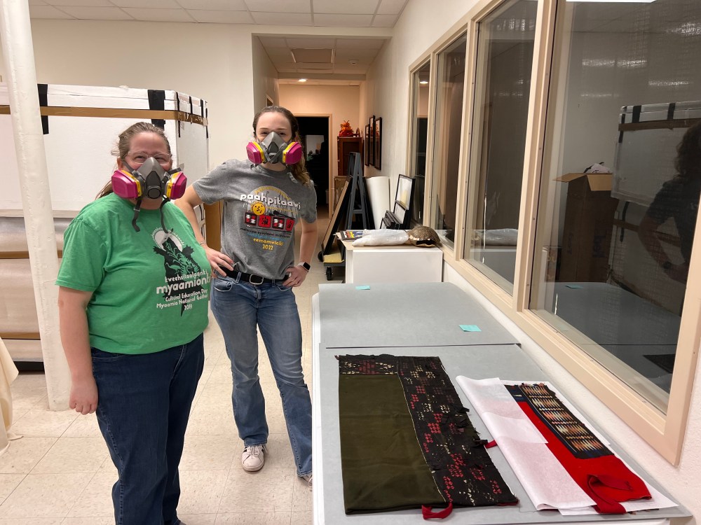 Posing for a photo with ribbonwork pieces while wearing protective masks