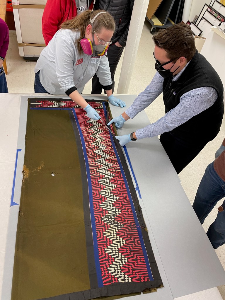 A man and woman carefully handle a blanket