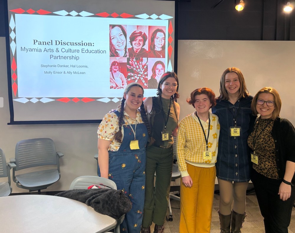 A group of panelists posing for the camera in front of the presentation title slide