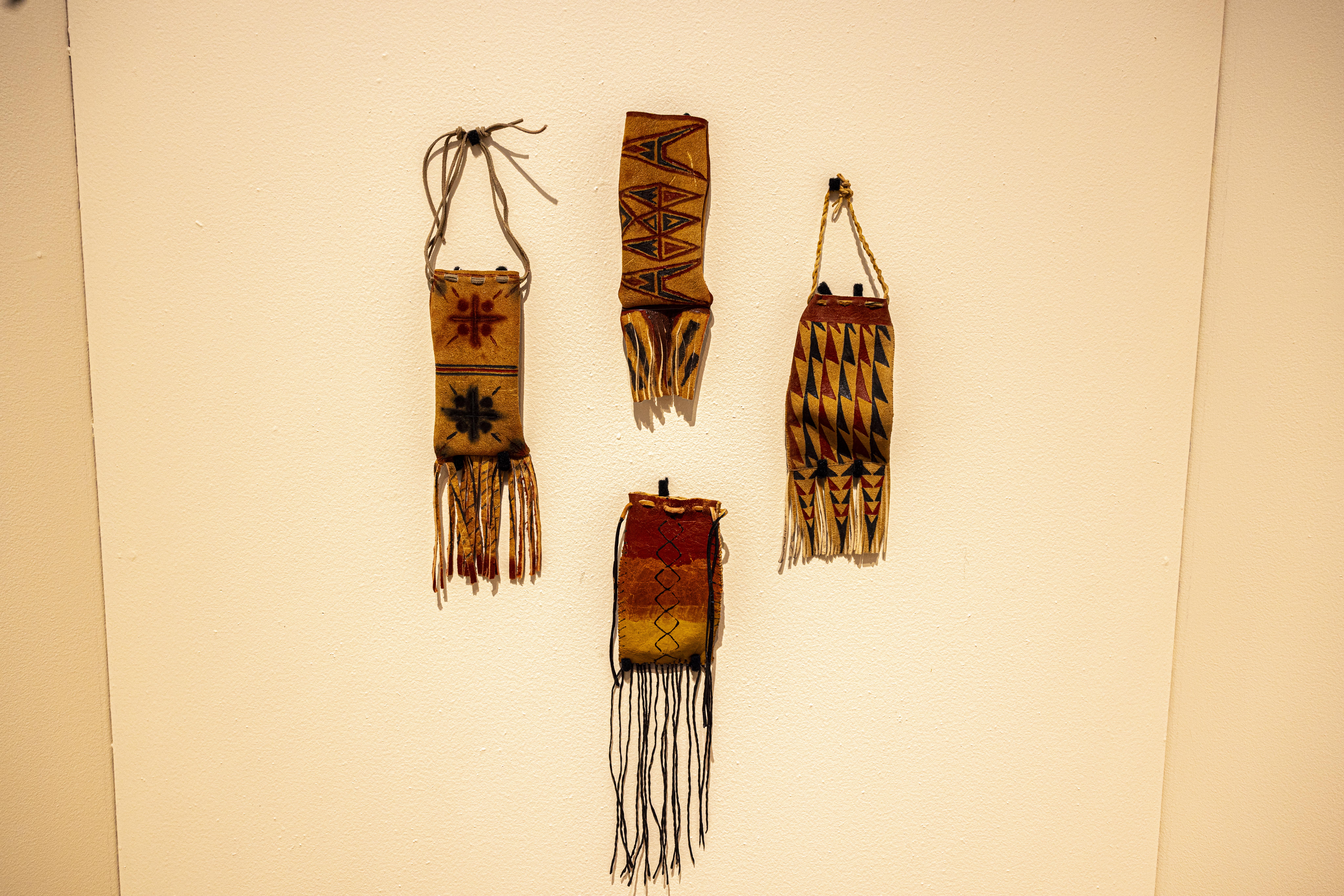 Small hide bags with painted designs created by hide painting workshop participants