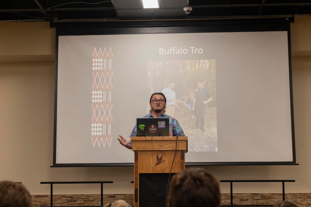 A man standing at a podium in front of a projector screen during a presenation