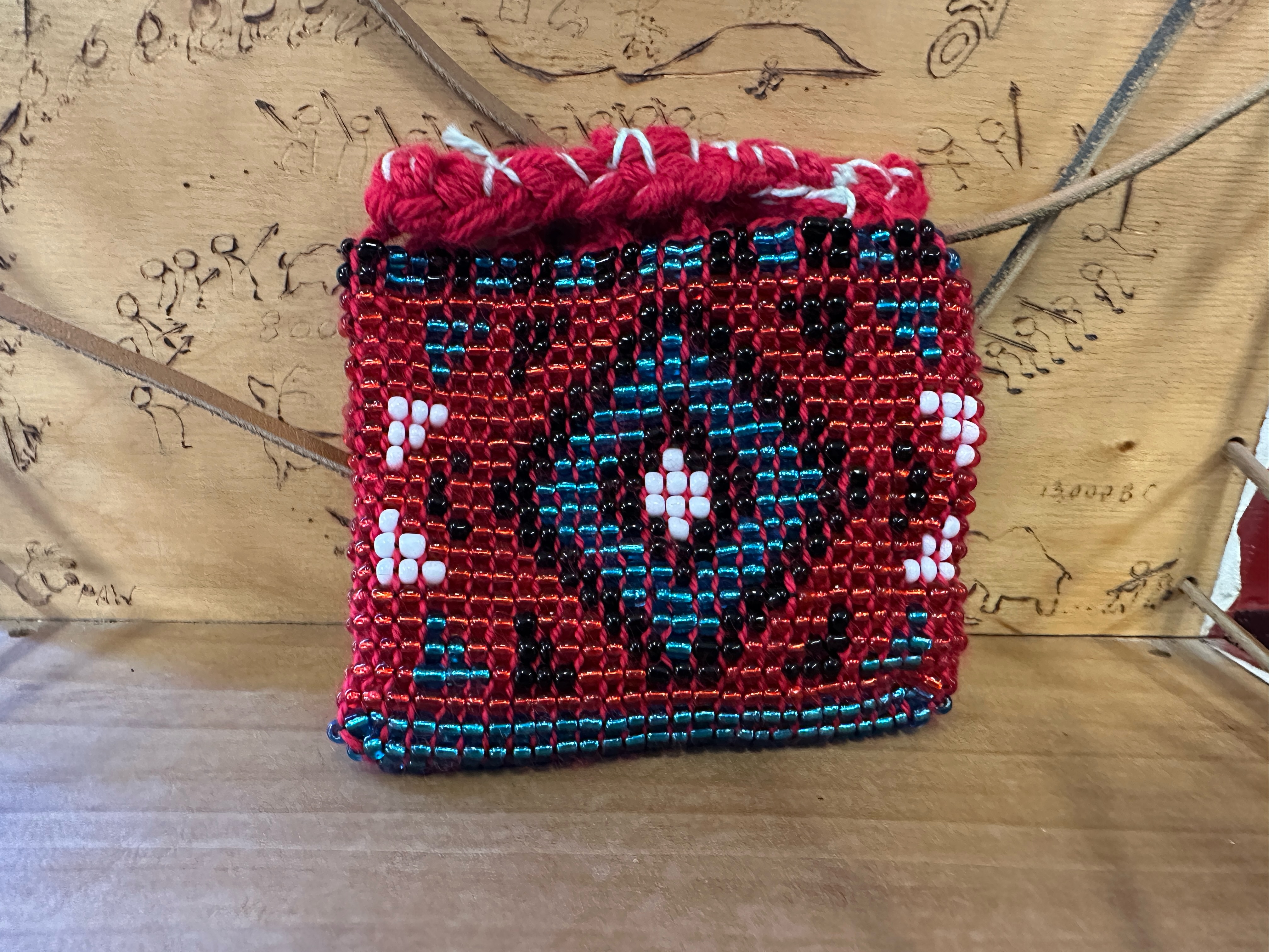 A beaded back featuring a diamond pattern in white, black, blue, and red glass beads.