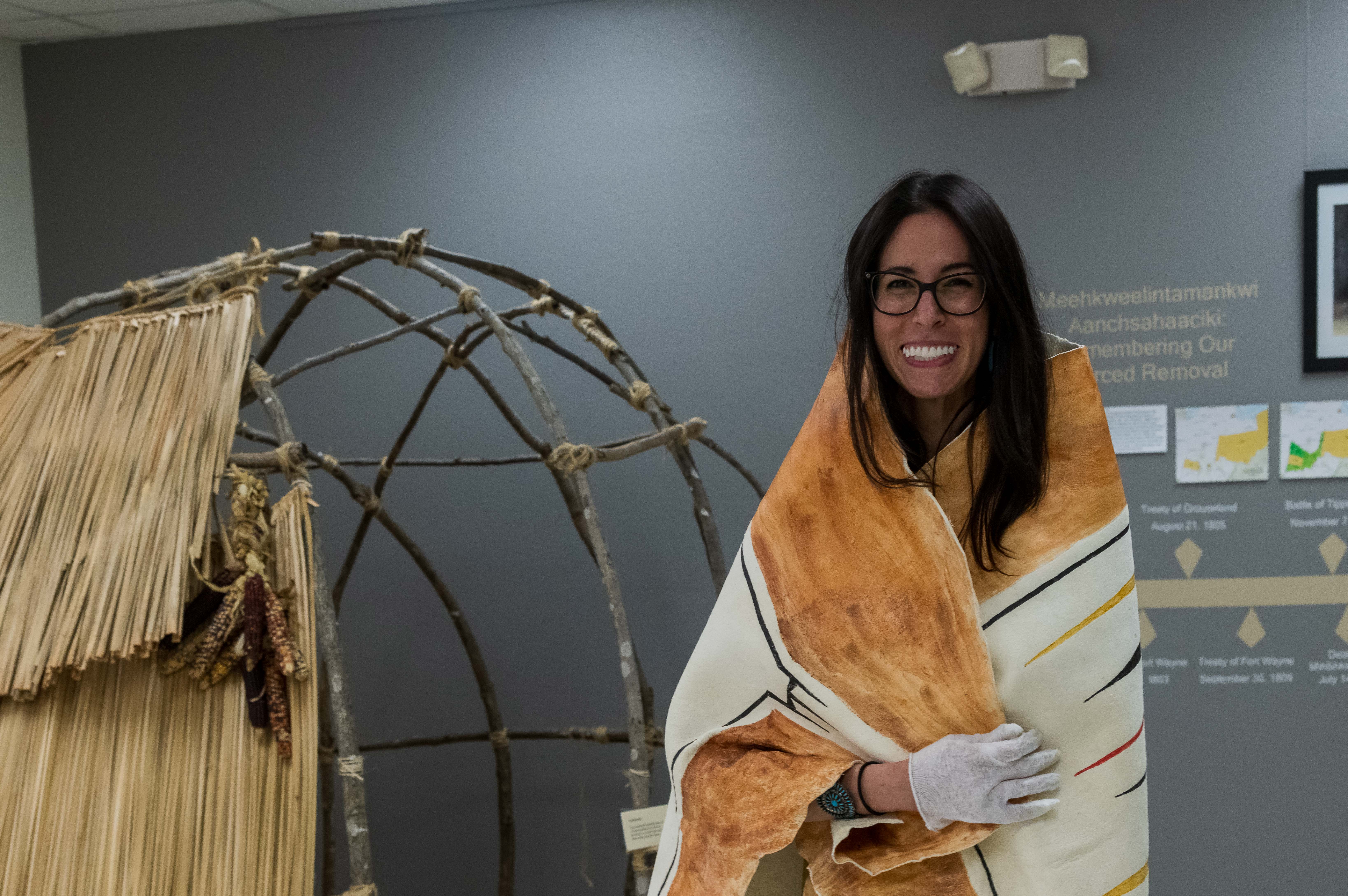 A woman wrapped in a replica painted hide robe. It is wrapped around her shoulders and held together across her chest.